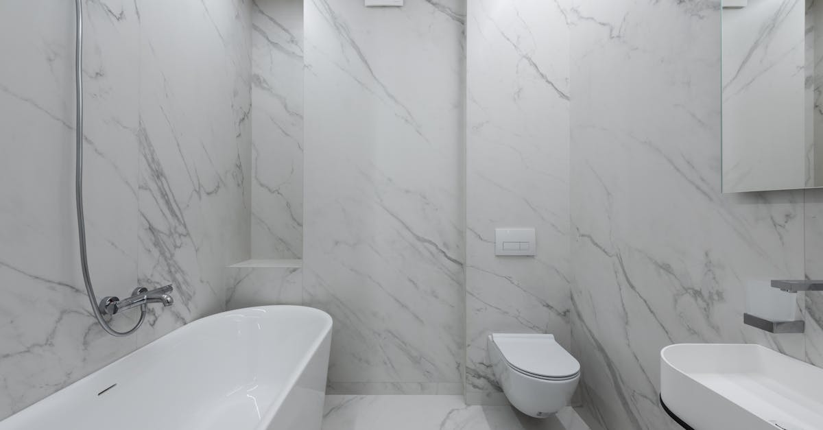 interior of stylish bathroom with marble walls and bath placed near toilet and ceramic sink in light